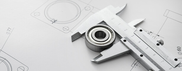 Bearing with vernier caliper and drawings on table of engineer, closeup