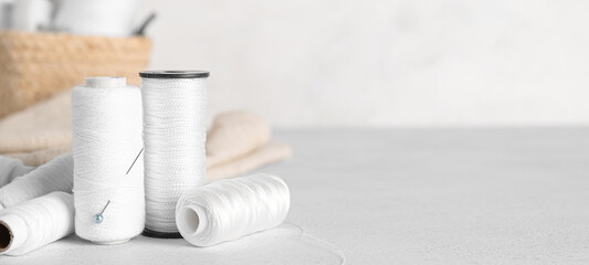 White threads with pin on light background with space for text