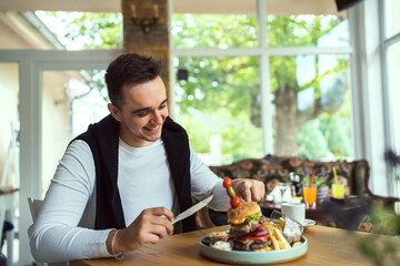 one young man sit at table eat burger and chips at restaurant