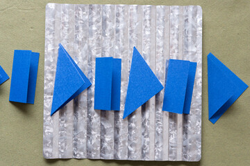 folded paper shapes on galvanized corrugated metal plate and rough green paper