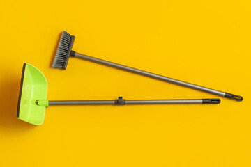 Cleaning broom with dustpan on yellow background
