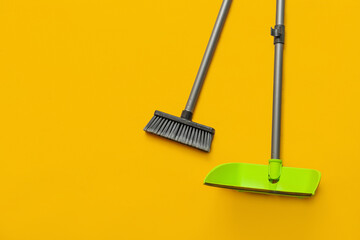 Cleaning broom with dustpan on yellow background