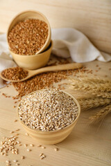 Bowl with pearl barley on wooden background