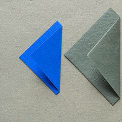 folded blue and green paper triangle shapes on rough green paper