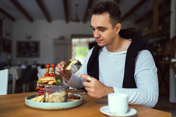 one young man sit at table eat burger and chips at restaurant