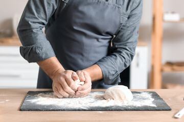 Fototapeta na wymiar Male baker preparing dough at table in kitchen, closeup