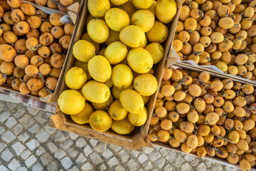 Lemons and loquats fruits in wooden boxes on farmers market in Portugal