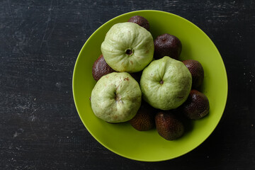 guava and salak fruit are on the green plate