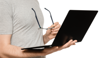A man holds a laptop in one hand and glasses in the other. Slim ultrabook in matte black with a touch screen. The concept of fatigue from working at the computer.
