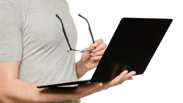 A man holds a laptop in one hand and glasses in the other. Slim ultrabook in matte black with a touch screen. The concept of fatigue from working at the computer.