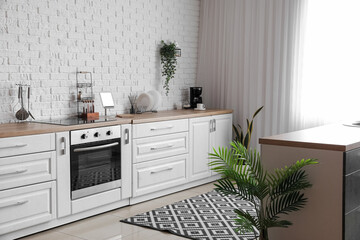 Interior of light kitchen with white counters and electric oven