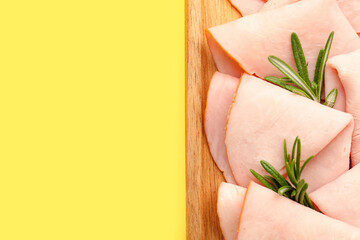 Board with slices of tasty ham, rosemary and peppercorn on yellow background