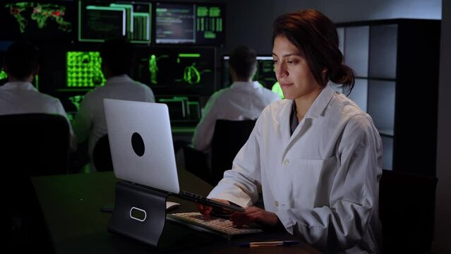 Female Medical Research Scientist using computer laptop. Neurologist Solving Puzzles of the Mind and Brain. In the Laboratory with Multiple Screens Showing Images. High quality 4k footage
