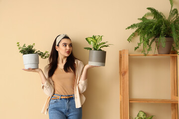 Young woman with green houseplant near beige wall