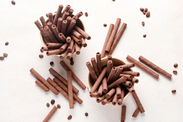 Bowls with delicious chocolate wafer rolls and coffee beans on white background