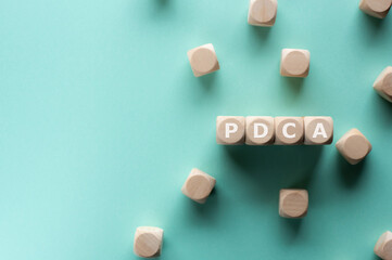 There is wood cubes with the word PDCA. It is an acronym for Plan, Do, Check, Act an eye-catching image.
