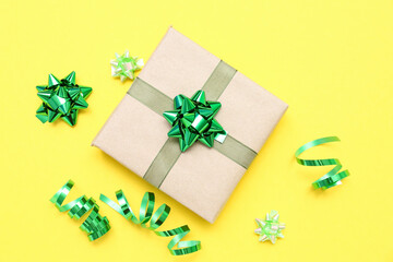 Gift box with green bows and serpentine on yellow background