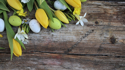 Background easter. A yellow tulips and easter eggs on a wooden rustic background. Copy space. Flat...