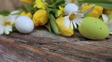 Background easter. A yellow tulips and easter eggs on a wooden rustic background. Copy space. Flat Lay.