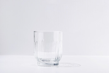 Transparent faceted water glass with shadow from harsh lighting
