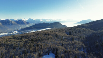 Panoramic view of snowy mountains in winter. Foggy mountains. Woods in front of the mountains.