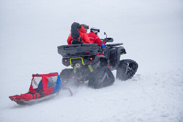 The mountain rescue team is heading out to save a person in the mountains during winter, using a...