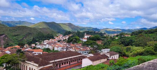Wide view City of Ouro Preto, Minas Gerais, Brazil. Landscape with historical houses, mountains and a blue sky with clouds