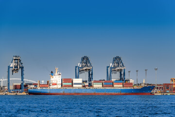 東京湾のコンテナ貨物船とガントリークレーン