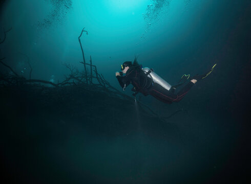 diver diving above a halocline in angelita cenote