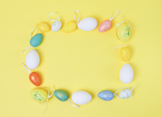Decorative Easter eggs are arranged in a square frame on a yellow background .