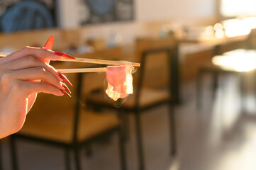 Woman's hand holding bacon with chopsticks