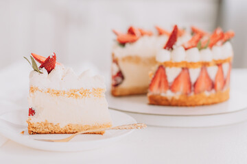 Sliced piece opposite mousse cake with strawberries on white table.