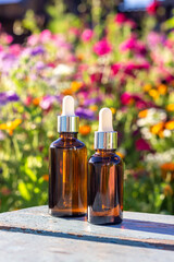 Brown glass dropper bottles with serum, essential oil or other cosmetic product on bright floral background. Natural Organic Spa Cosmetic Beauty Concept Mockup Front view