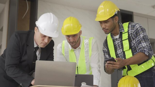 Architect discussing blueprints on laptop with construction manager Engineer talking to contractor consultant on construction site about construction project and business workflow in new building