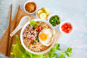 noodles bowl with boiled egg minced pork vegetable spring onion lemon lime lettuce celery and chili on table food , instant noodles cooking tasty eating with bowl noodle soup