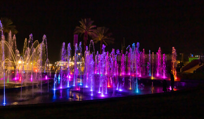 Enchanting grandiose musical performance - water and light show of a musical fountain on the embankment, in the center of the city of Eilat in southern Israel - obrazy, fototapety, plakaty