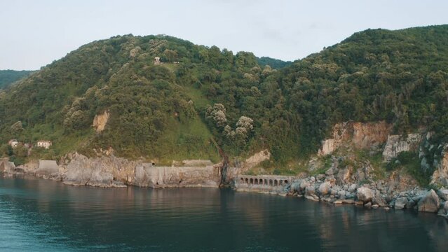 Drone view of the lighthouse in the trees, the white lighthouse building built on the edge of the cliff
