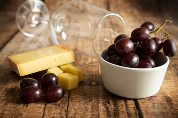 red grapes with cheese and a wineglass on a wooden background