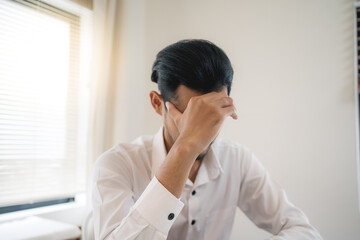 Asian businessman headache stressed because of work mistake problems about profit losses to be risk for fired from her job