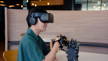 Male student wearing a wireless controller that moves a robotic hand. Test your control system and learn about your interests in order to develop and help people with disabilities in the future.