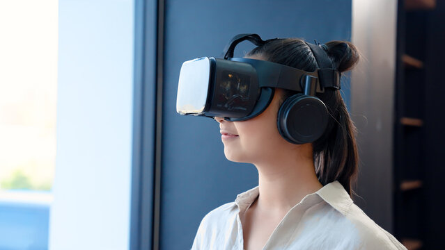Close-up shot of Asian woman doing power. using vr glasses Looking at 3D stereoscopic images. Future models. woman sitting in ocean room university operating area while waiting to enter the classroom