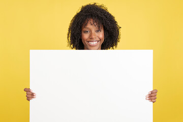 Woman with afro hair holding a blank panel while smiling
