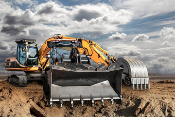 Bulldozer or loader moves the earth at the construction site against the blue sky. An earthmoving...
