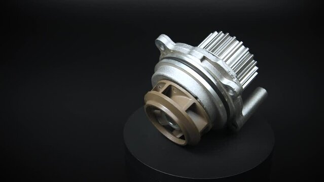 Auto parts car spare parts on a black background. The new ICE water cooling pump rotates on a turntable around its axis. Auto parts store. Engine car details