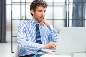 Young modern business man working using computer while sitting in the office.