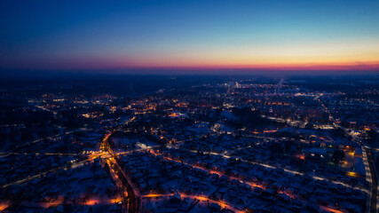 Flight over a city illuminated by a sunset flare. City lantern lights from above. A small town from above. Selective soft focus