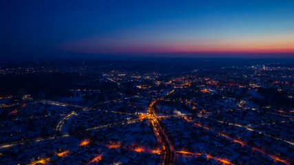 Flight over a city illuminated by a sunset flare. City lantern lights from above. A small town from above. Selective soft focus