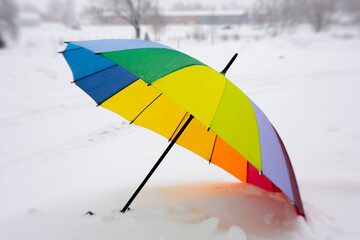 Colorful umbrella in winter on the snow. lgbt umbrella on snow alone