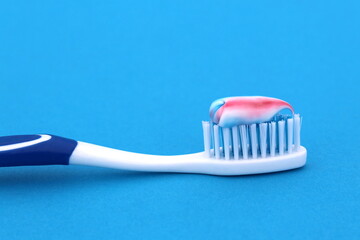 On a blue background lies a toothbrush with paste.