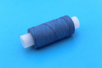 Fototapeta na wymiar On a blue background lies a spool of blue thread.